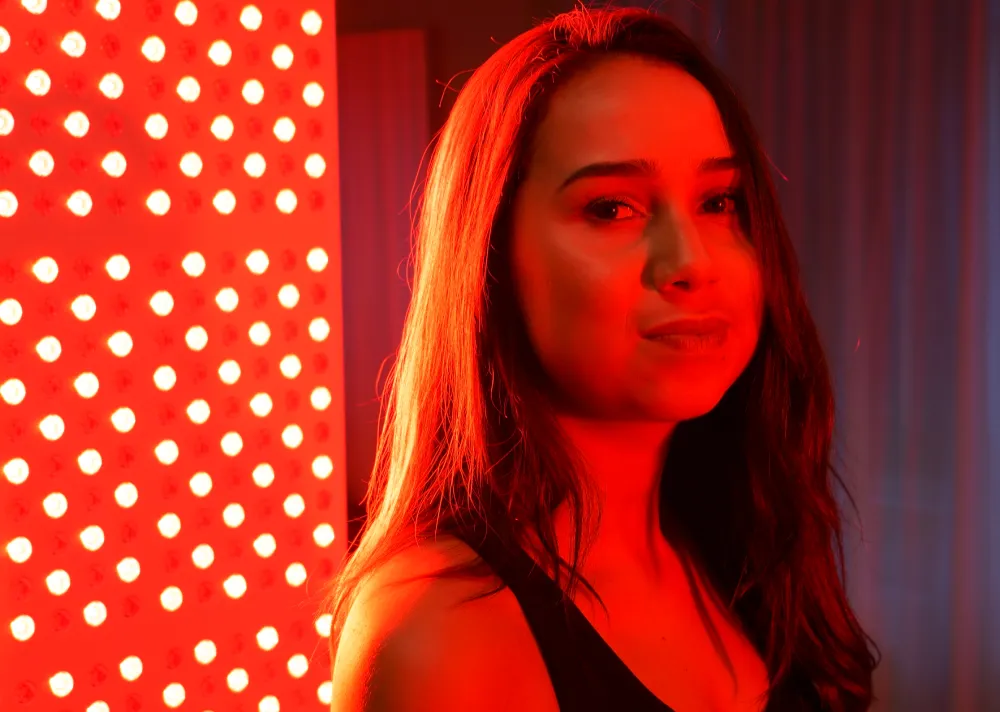 vrouw kijkt in de camera tijdens rood licht therapie sessie